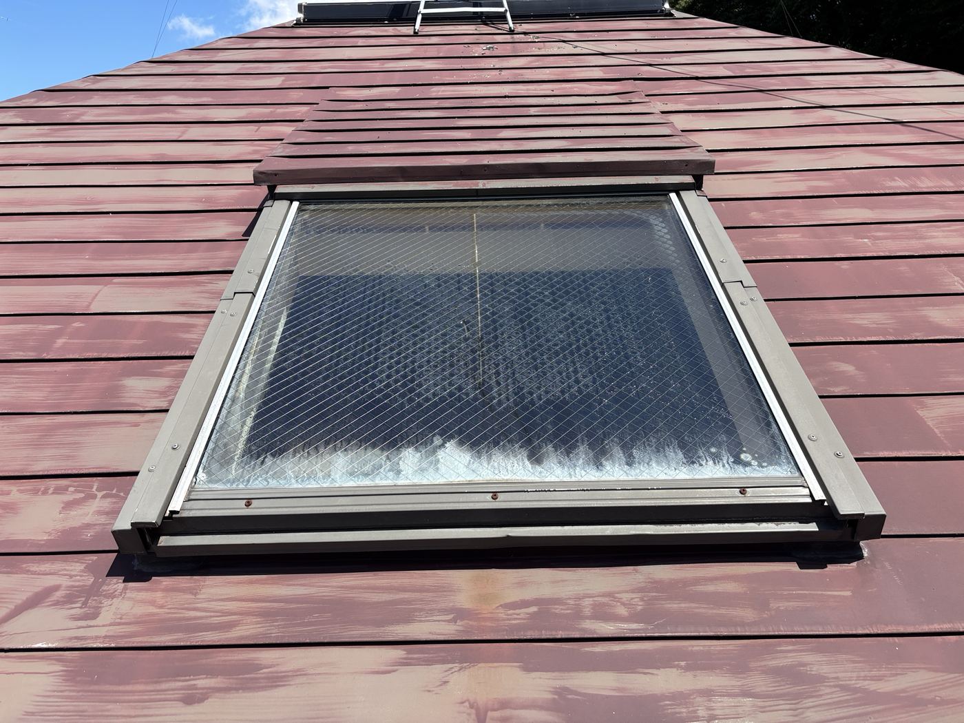 雨漏りしたVELUX(ベルックス)の天窓を、屋根の下側から見上げたところ。金属屋根の塗装が色あせ、天窓の下の枠にビスのサビが見える
